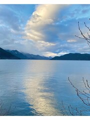 A sunny winter afternoon in Harrison Hot Springs, British Columbia, Canada. Blue sky, white cloudy, and beautiful reflection. Some waves and thin ice on the lake surface.