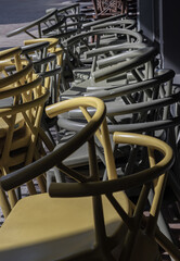 detail of Stack of Dark green (Khaki color) and Yellow plastic chairs.