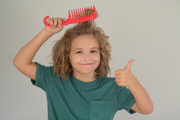 Boy brushes his hair. Cute child with comb. Blonde kid combs unruly hair. Kid boy with tangled long...
