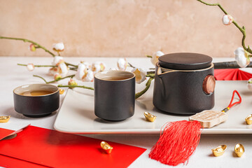 Teapot with cups, sakura and Chinese symbols on white table. New Year celebration