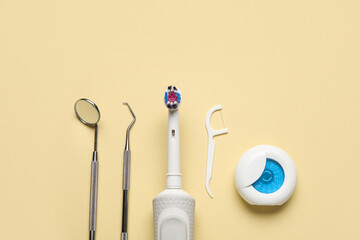 Dental tools with electric brush, toothpick and floss on yellow background