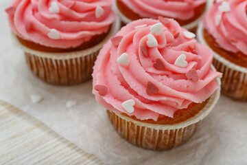 Baking paper with cupcakes for Valentine's Day on wooden background, closeup