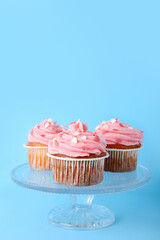 Glass stand with cupcakes for Valentine's Day on blue background