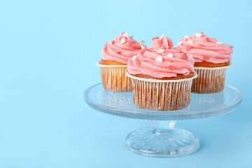 Glass stand with cupcakes for Valentine's Day on blue background