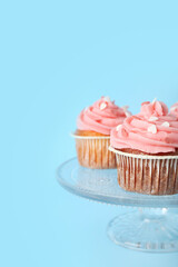 Glass stand with cupcakes for Valentine's Day on blue background