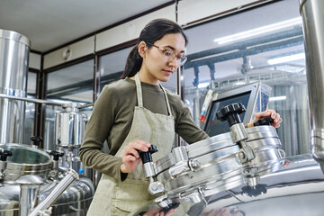 Female young engineer working on equipment to control the process of brewing