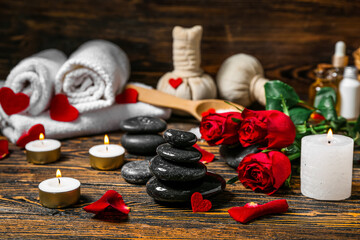 Spa stones with candles and roses on dark wooden table, closeup. Valentine's Day celebration