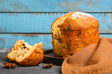 Board with cut Panettone and anise on color wooden background