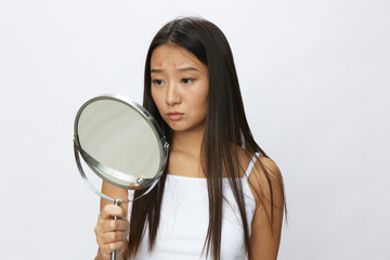 Asian woman with mirror in hand facial skin problems, acne and inflammation, red rash and...
