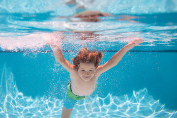 Child in pool in summer day. Underwater child swims in pool, healthy child swimming and having fun...