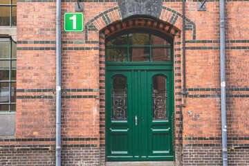 Green wooden door withe number 1. sign on the left side