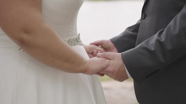 Close up, anonymous heterosexual plus sized couple holding hands on wedding day, slow motion