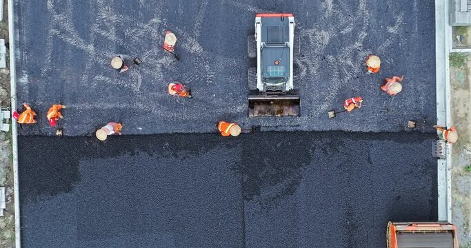 Aerial footage of construction site is laying new asphalt pavement. road workers and road construction machinery scene. Top view.