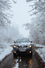 a snow-covered car in the middle of a winter forest