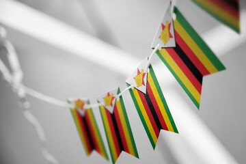 A garland of Zimbabwe national flags on an abstract blurred background - obrazy, fototapety, plakaty