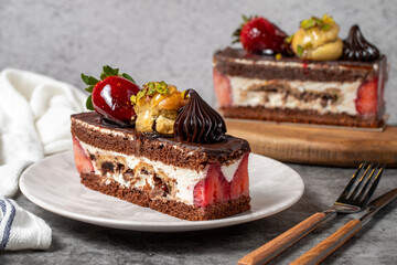 Strawberry and chocolate cake on a dark background. Slice of layered chocolate cake. Bakery cake products. close up