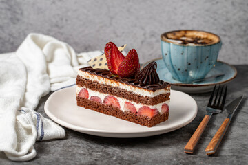 Strawberry and chocolate cake on a dark background. Slice of layered chocolate cake with coffee cup. Bakery cake products. close up