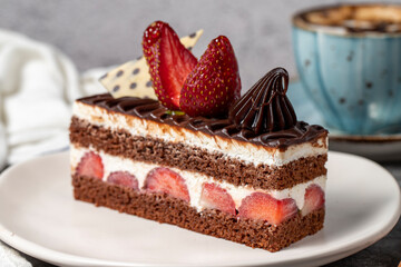 Strawberry and chocolate cake on a dark background. Slice of layered chocolate cake with coffee cup. Bakery cake products. close up