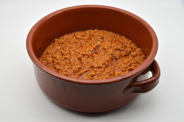 Italian bolognese ragu in a crock pot, isolated on white background. Beef and pork loin ragu. Delicious comfort healthy food.