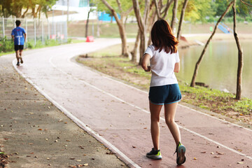 Woman runner running through the park. Young girl running.