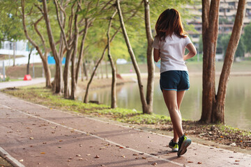 Woman runner running through the park. Young girl running.