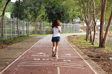 Woman runner running through the park. Young girl running.