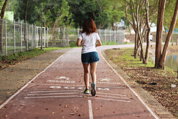 Woman runner running through the park. Young girl running.