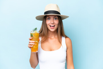Young beautiful woman holding a cocktail isolated on blue background with surprise and shocked facial expression