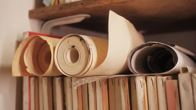 Oil paintings in creative workroom. Canvases roll and old paintings in workshop. Art storage shelves. Storing canvas, frame, papers and boards.