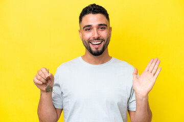 Young Arab man holding home keys isolated on yellow background with shocked facial expression