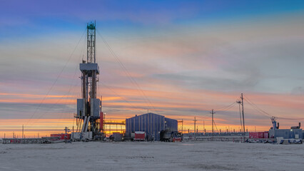 Obraz premium Drilling wells at an oil and gas field in the Arctic region. Production infrastructure and drilling rig. Beautiful winter sky. Polar Day