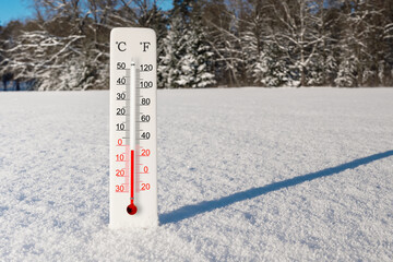 White celsius and fahrenheit scale thermometer in snow. Ambient temperature minus 3 degrees celsius