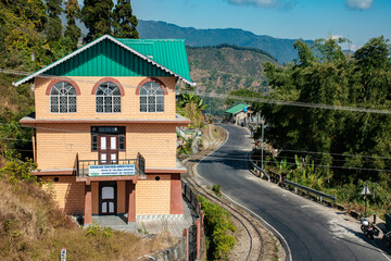 Fototapeta na wymiar An office building of Gorkha Teritorial Administration at Kurseongwith beautiful curved road and Darjeeling toy train track.