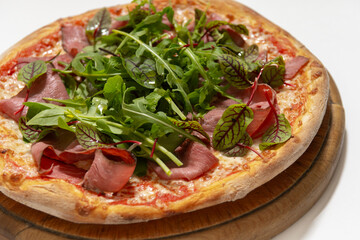 pizza with ham and basil on desk on white background