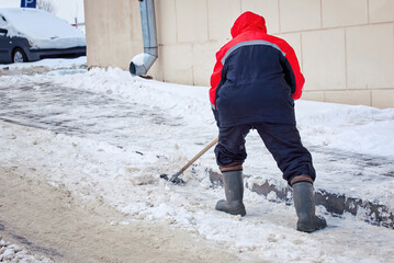 Worker remove ice and clear snow from paving slabs using an icebreaker. Man breaks ice with steel...