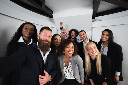 Group of happy colleagues of diverse ethnicity take a selfie photo with smartphone. Teamwork, cooperation, partnership and unity concept.