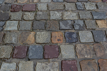 Granite dirty paving stones in the city. Road from paving stones for background and texture. The old road of granite paving stones