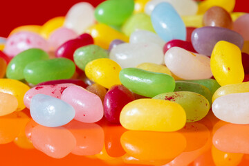 Jelly beans sweets candy piled on an orange background. High sugar unhealthy food concept