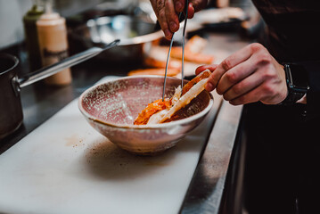hand of chef in restaurant cooking crab leg