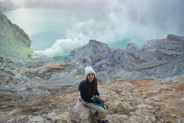 tourist girl inside Ijen volcano crater in Indonesia with acid lake