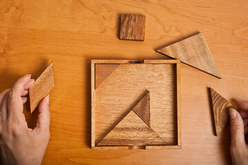 playing with a wooden tangram puzzle game 