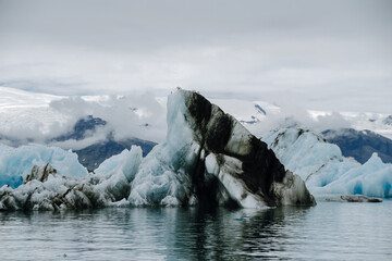 A colony of seagulls sitting on an iceberg in the Jökulsárlón glacier lagoon in Iceland, which has broken away from the Breiðamerkurjökull glacier tongue. With a view of Hvannadalshnúkur - obrazy, fototapety, plakaty