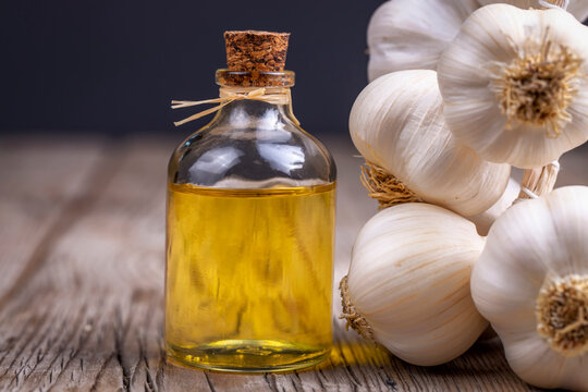 Fresh garlic and garlic oil on the wooden background