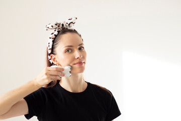 Beautiful young woman gives her face a self-massage with a microcurrent massage machine. Blank copy...