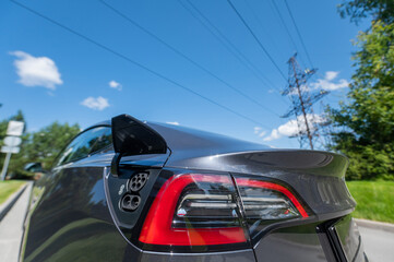 Close-up of a black electric car charging socket outdoors in summer.