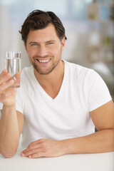 smiling young man holding a glass of water