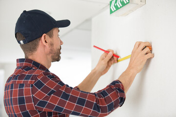 man measuring wall and marking position