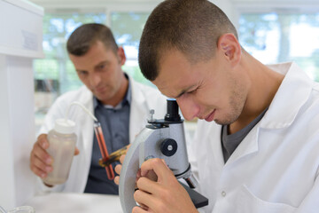 Obraz premium young scientist in uniform looking through a microscope