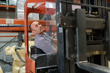 man using a forklift in warehouse racking - obrazy, fototapety, plakaty