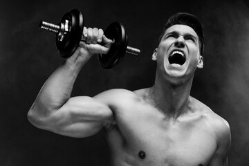 Black and white photo of handsome sportive strong-willed naked guy building muscles